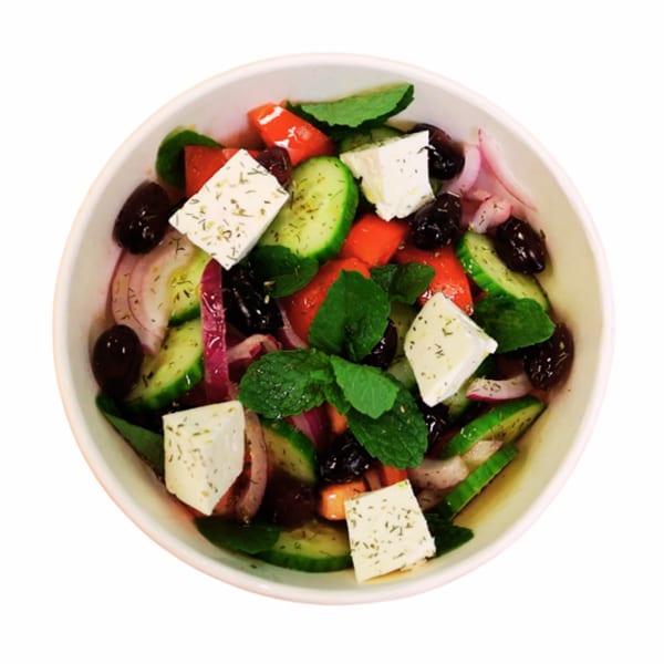 Overhead view of a vibrant Greek salad with feta, olives, cucumbers, tomatoes, and red onion.