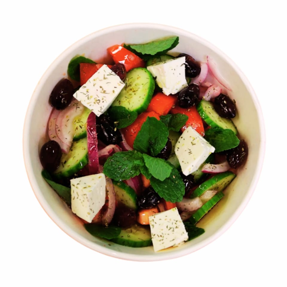 Overhead view of a vibrant Greek salad with feta, olives, cucumbers, tomatoes, and red onion.